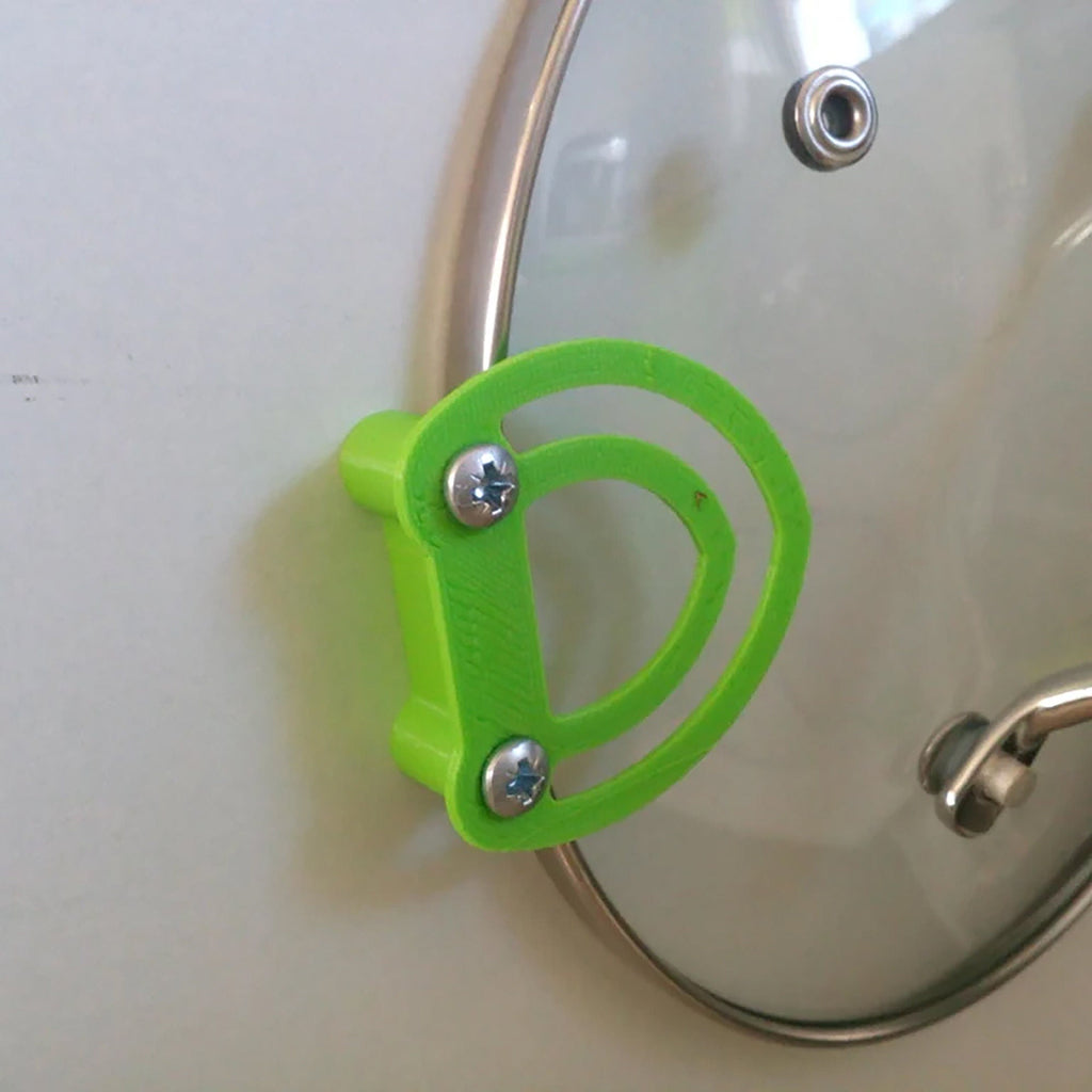 Pot lid holder clips mounted inside a kitchen cabinet door holding a glass lid, view 5