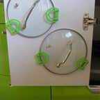 Pot lid holder clips mounted inside a kitchen cabinet door holding a glass lid