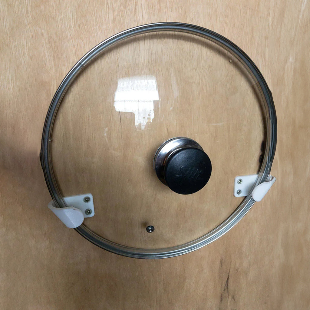 Pair of angled brackets holding a glass pot lid on a kitchen cabinet door