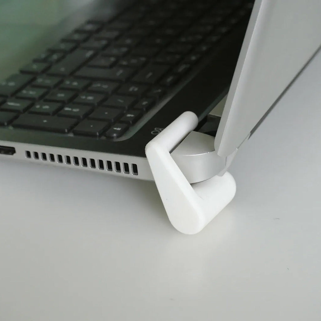 Clip-on laptop riser feet lifting the rear edge of a laptop for airflow