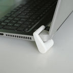 Clip-on laptop riser feet lifting the rear edge of a laptop for airflow
