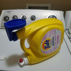 Detergent cup drip catcher on a Tide laundry bottle spout holding the measuring cup, view 2