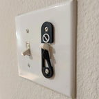 Light switch lock with pivoting arm and marked toggle cap on a wall switch, view 5