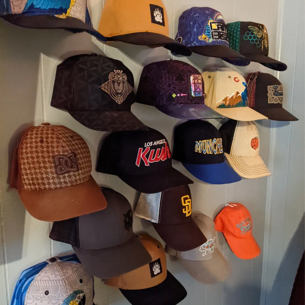 Wall mounted hat rack hooks displaying baseball caps in a row
