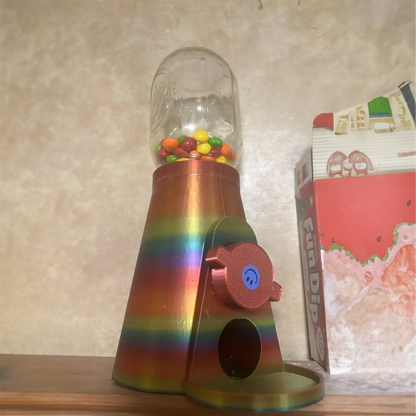 a rainbow colored candy dispenser on a shelf