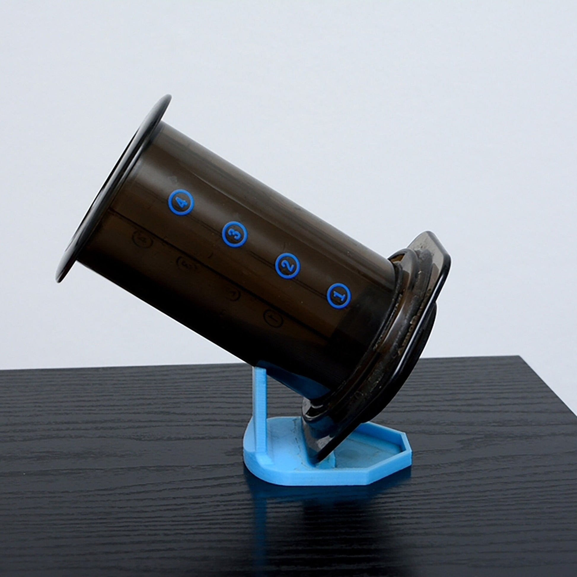 a black and blue coffee cup sitting on top of a blue stand