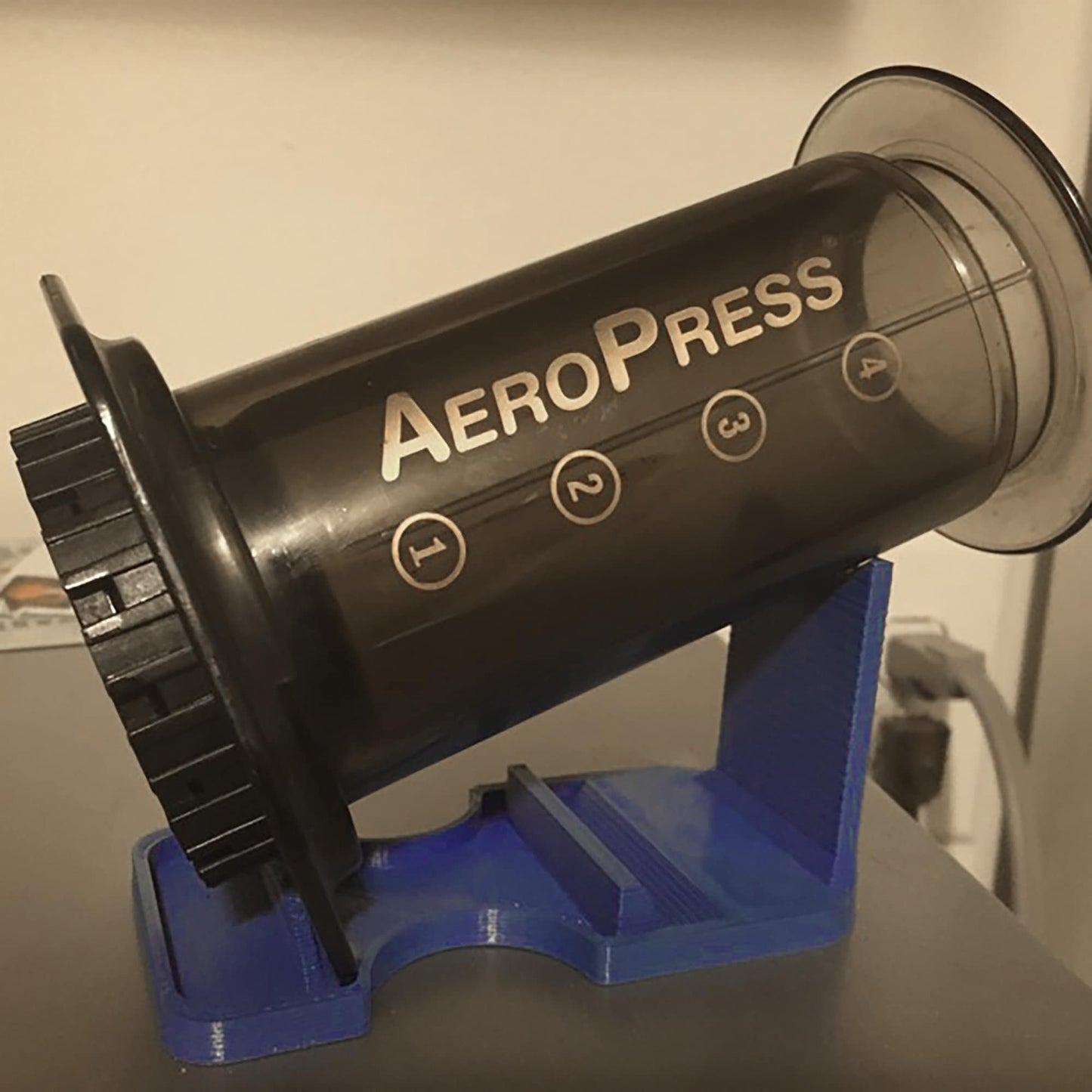 a black aeropress on a blue stand on a table