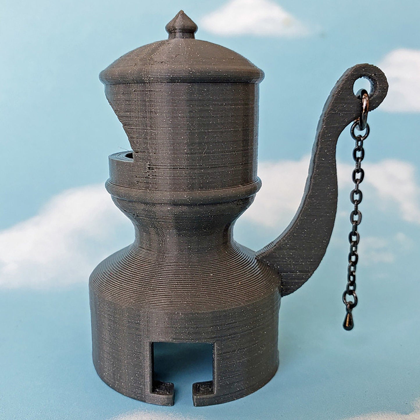 a miniature teapot with a chain attached to it