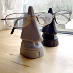 Nose shaped eyeglasses holder stand cradling a pair of glasses, view 2