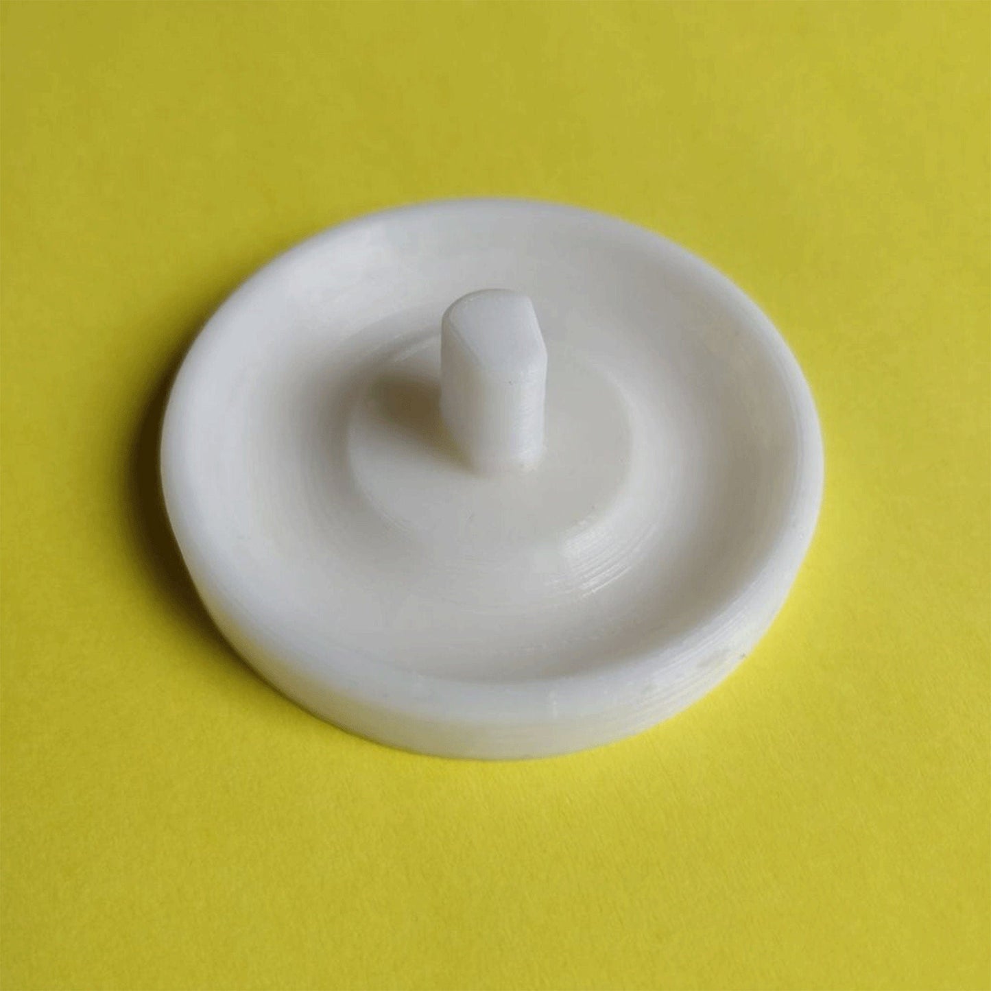 a white button sitting on top of a yellow surface