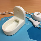 Wall mount holding an Oral-B toothbrush charging base with cable channel, view 2