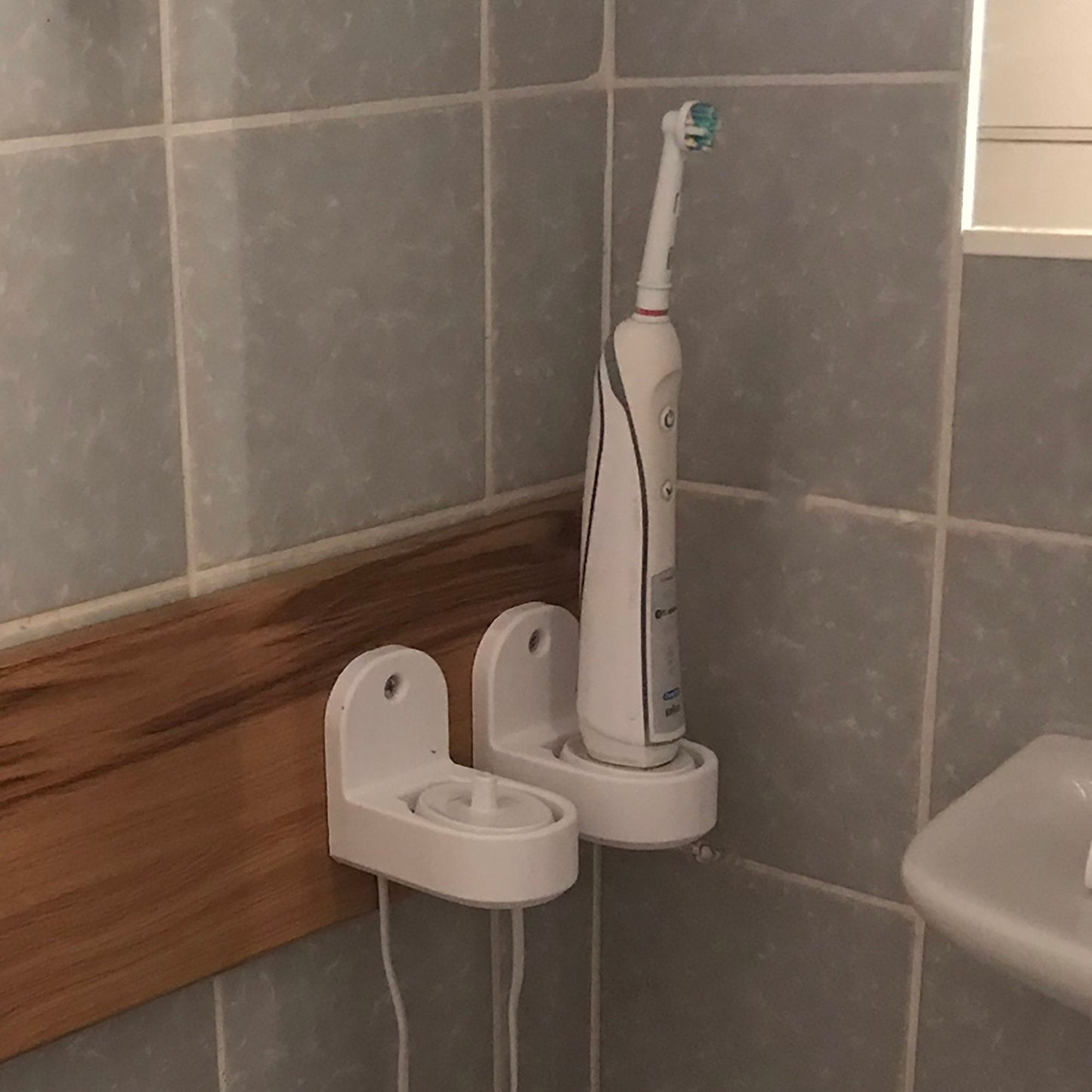 a white electric toothbrush sitting on a holder in a bathroom