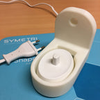 Wall mount holding an Oral-B toothbrush charging base with cable channel