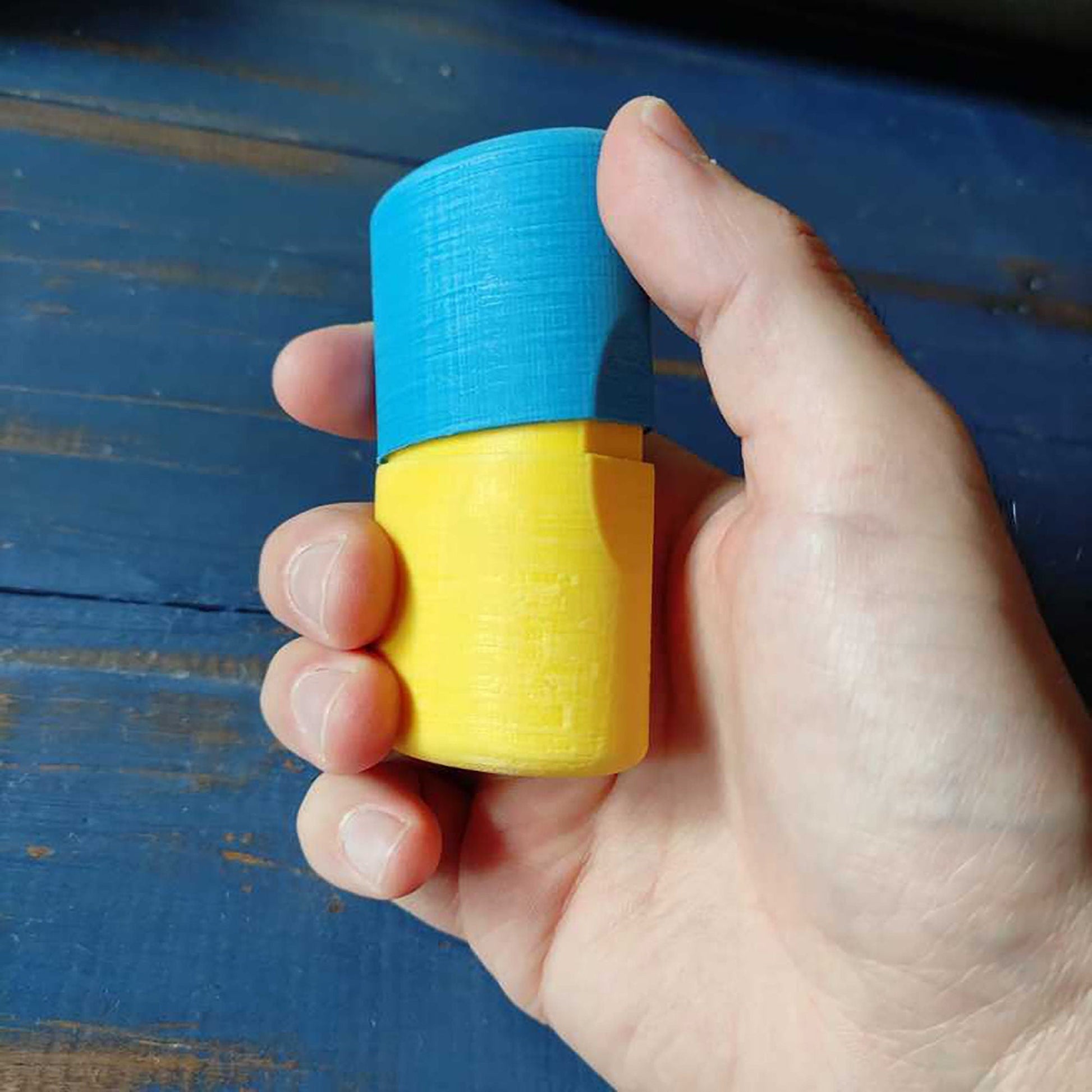 a hand holding a small blue and yellow object