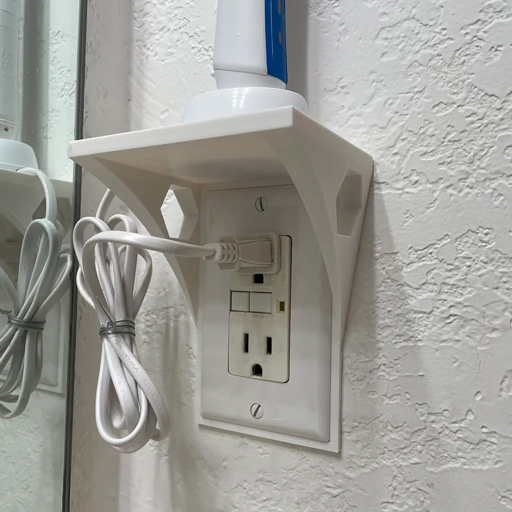Outlet shelf mounted over a wall outlet holding a phone while it charges, view 2