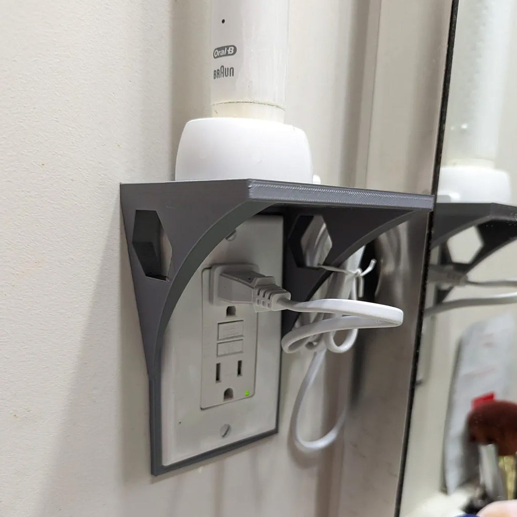 Outlet shelf mounted over a wall outlet holding a phone while it charges, view 3