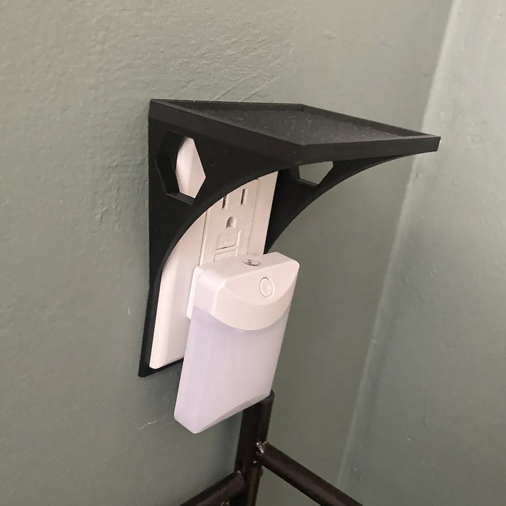 Outlet shelf mounted over a wall outlet holding a phone while it charges, view 4