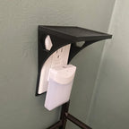 Outlet shelf mounted over a wall outlet holding a phone while it charges, view 4