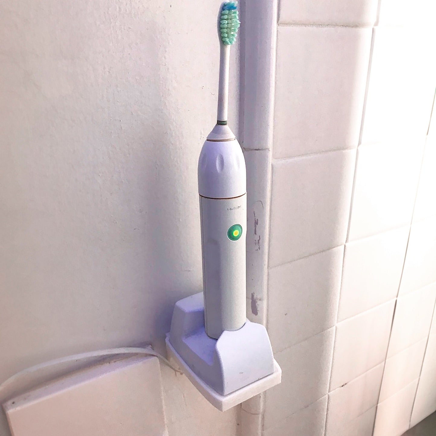 a white electric toothbrush mounted to a wall