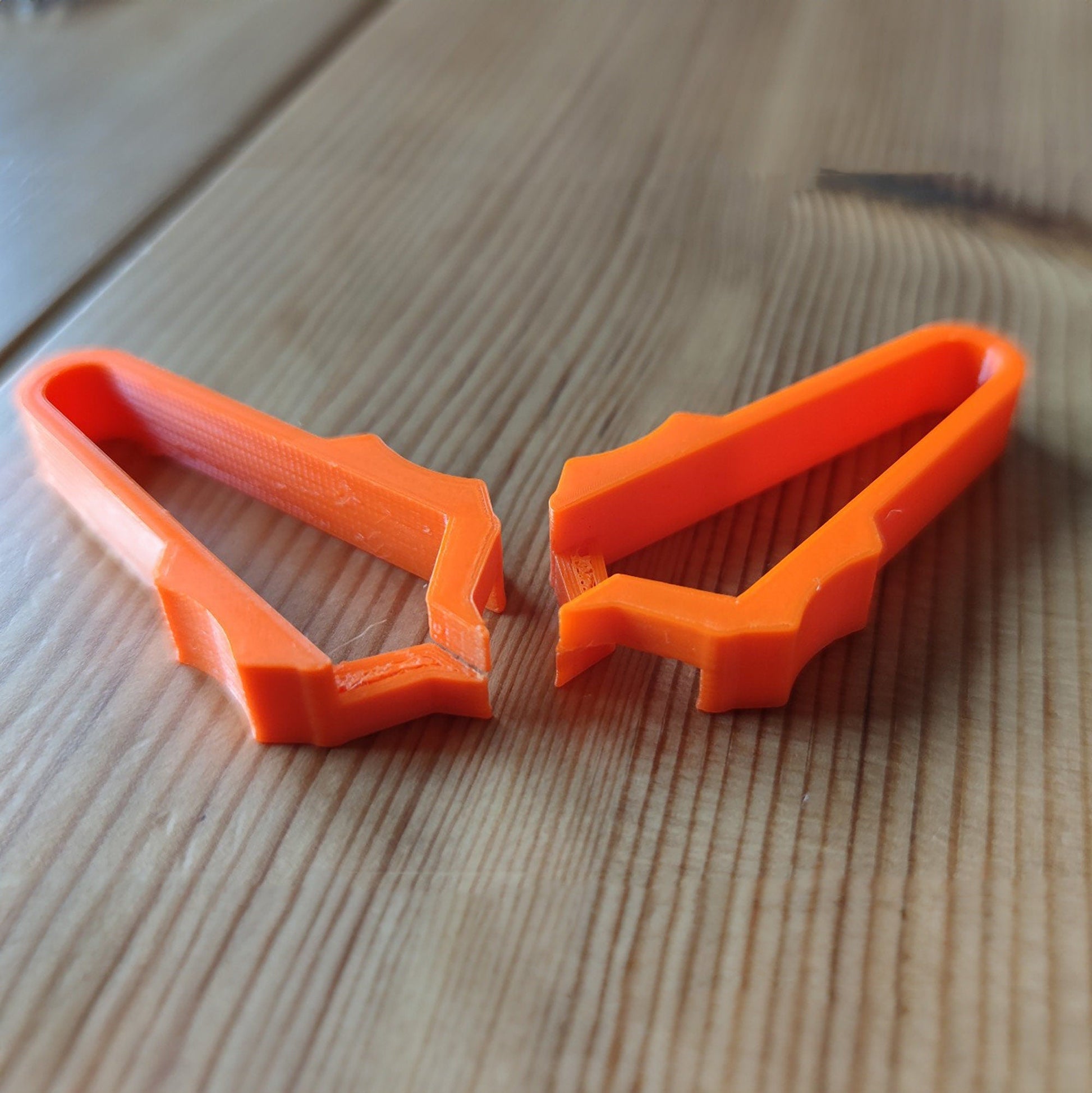 a pair of orange scissors sitting on top of a wooden table