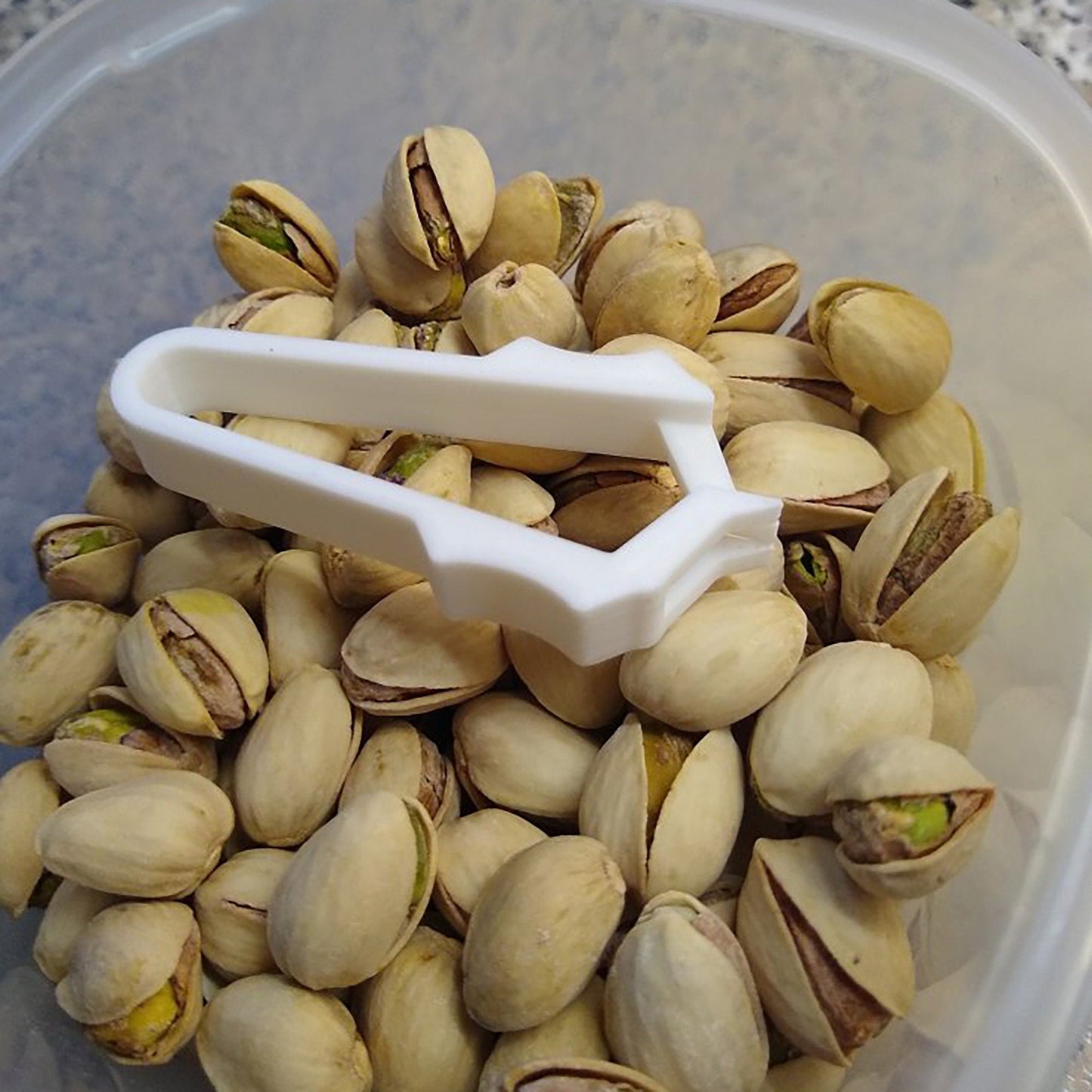 a plastic container filled with pistachios and a plastic scoop