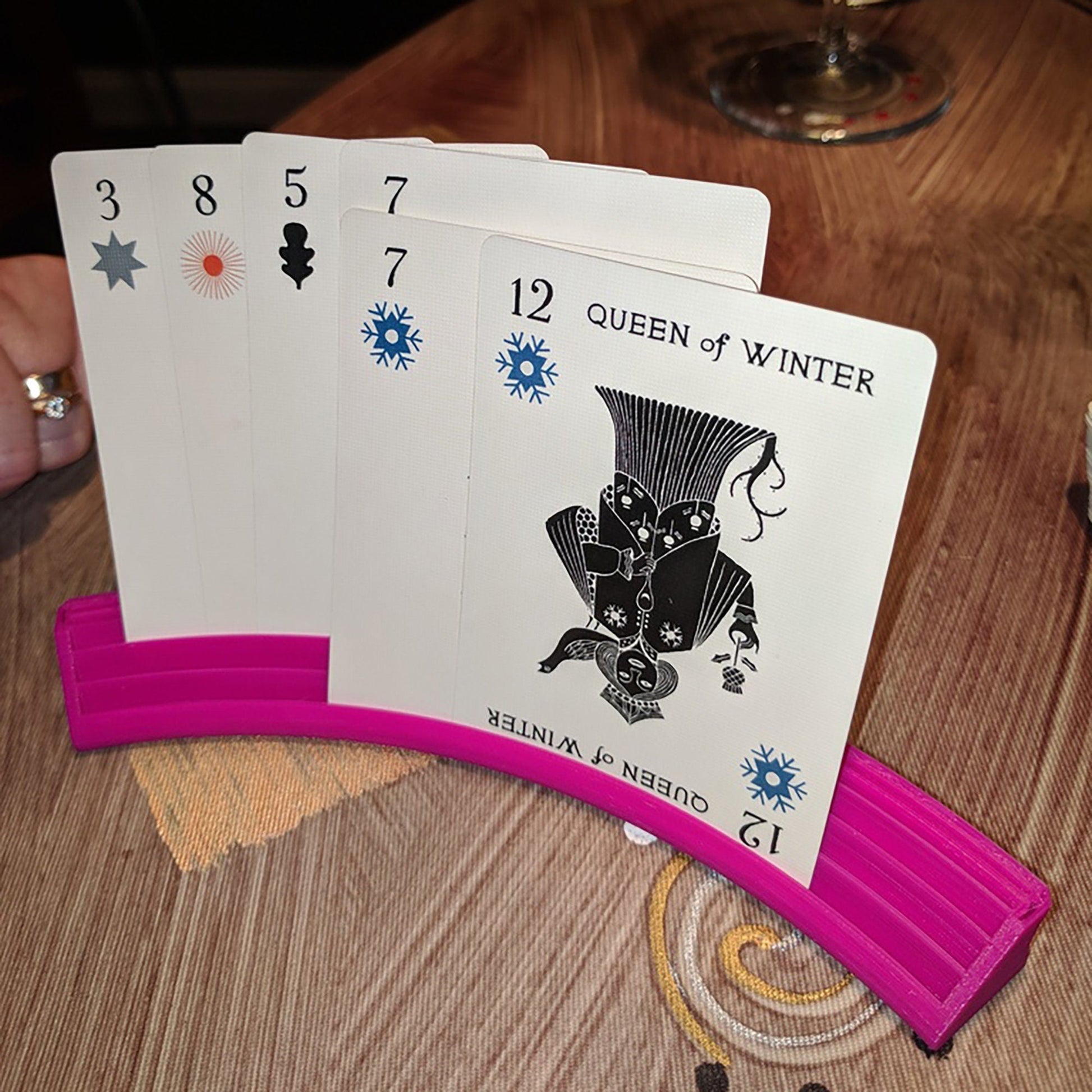 a person holding four playing cards on a table