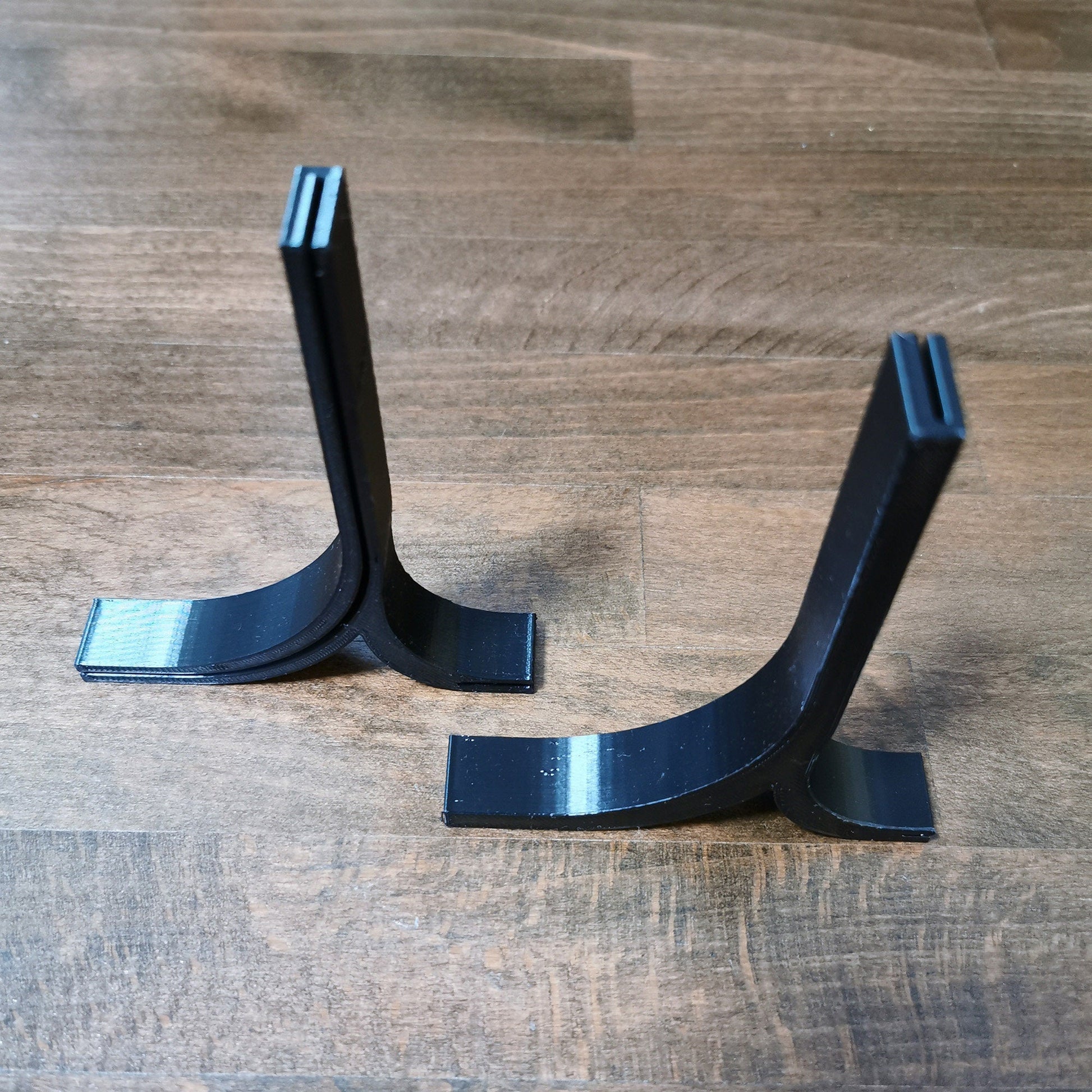 a pair of black metal brackets on a wooden floor