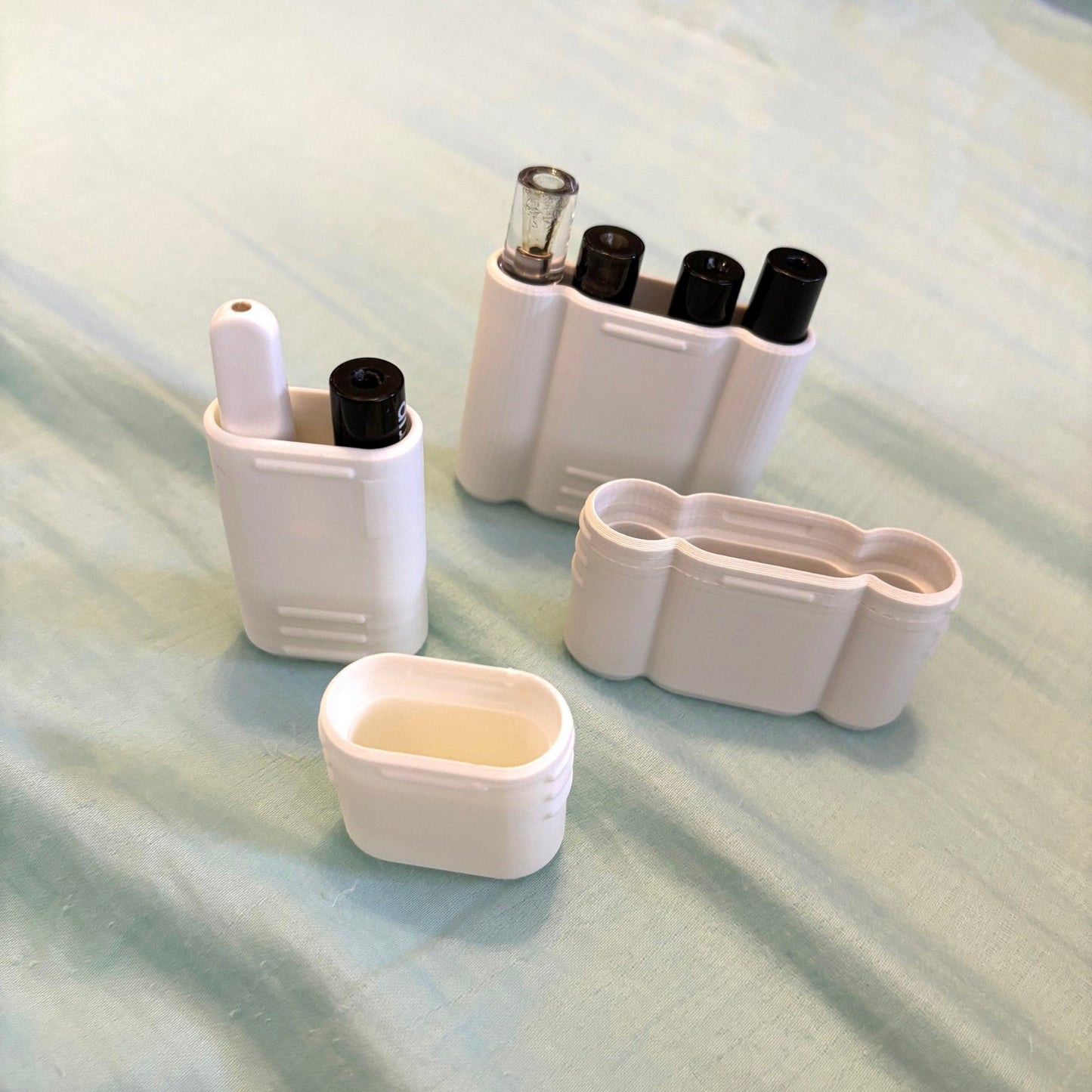 a set of four white containers sitting on top of a bed