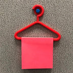 Mini coat hanger sticky note holder pinned to a cork board