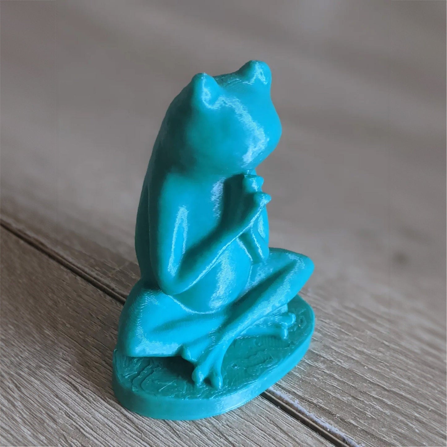 a blue frog figurine sitting on a wooden floor