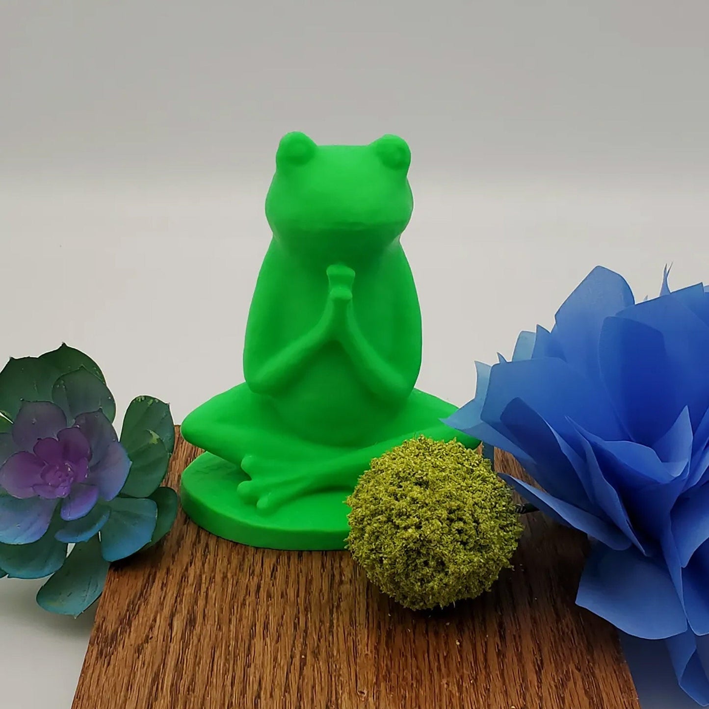 a green frog statue sitting on top of a wooden table