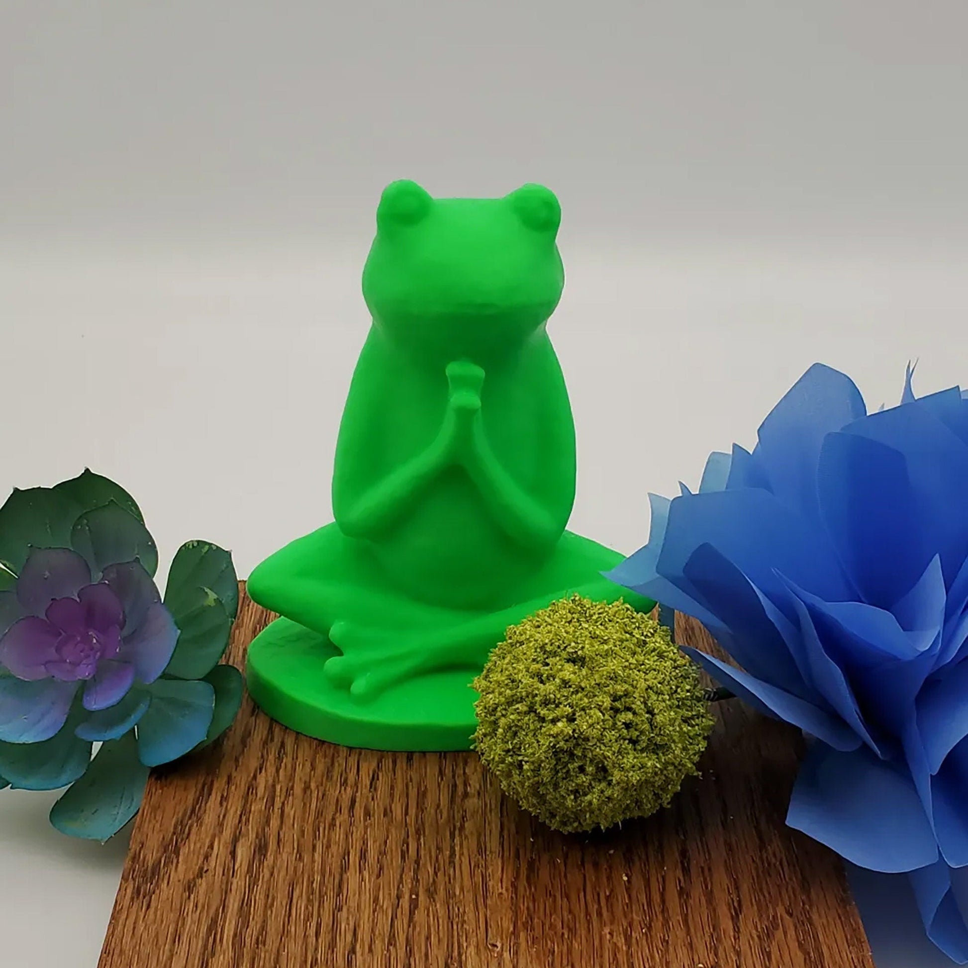 a green frog statue sitting on top of a wooden table