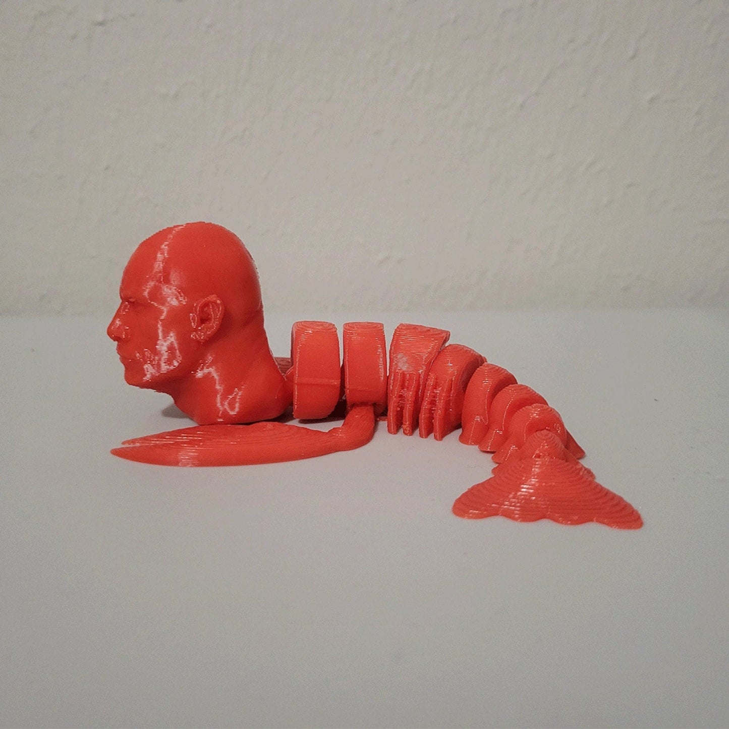 a red plastic model of a man laying on the ground