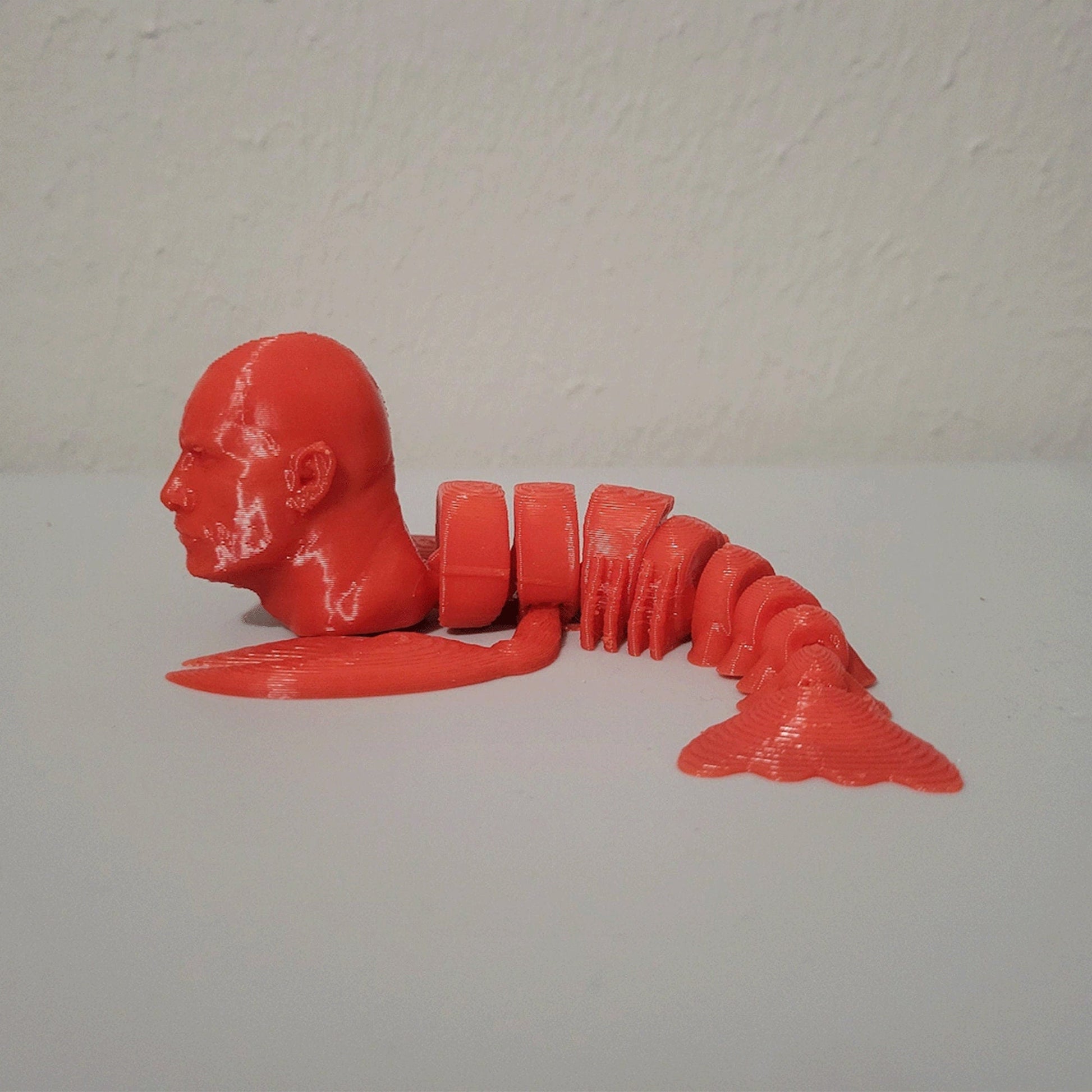 a red plastic model of a man laying on the ground