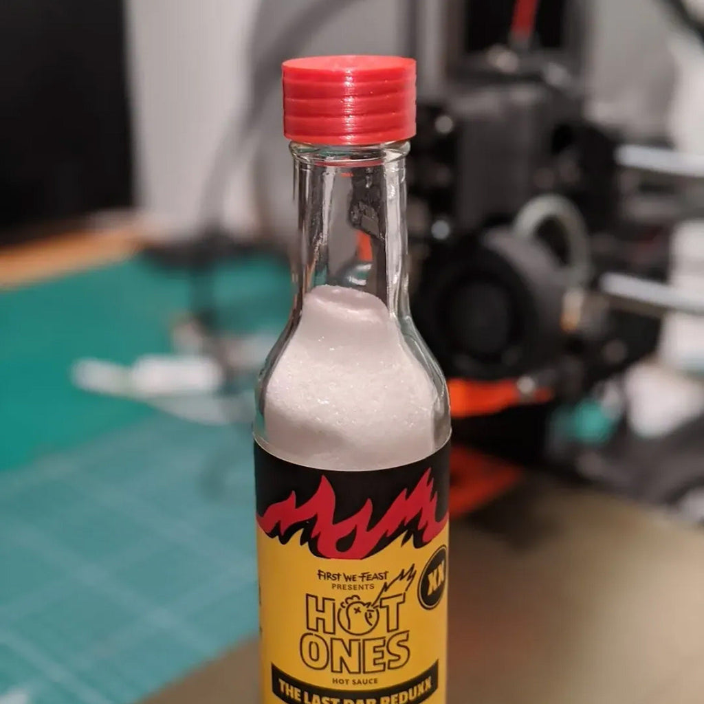 Salt shaker lid with seven holes screwed onto a hot sauce bottle, view 2