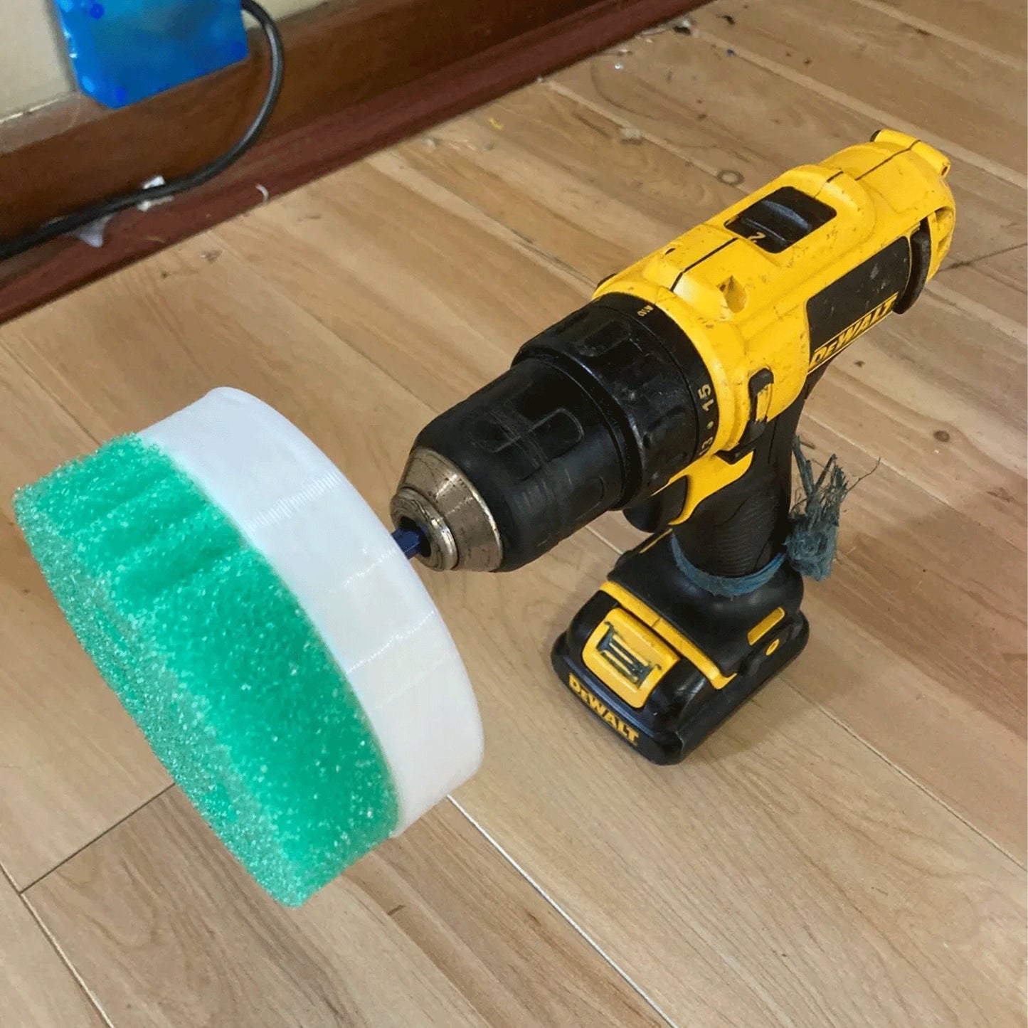 a drill and a sponge on a wooden floor