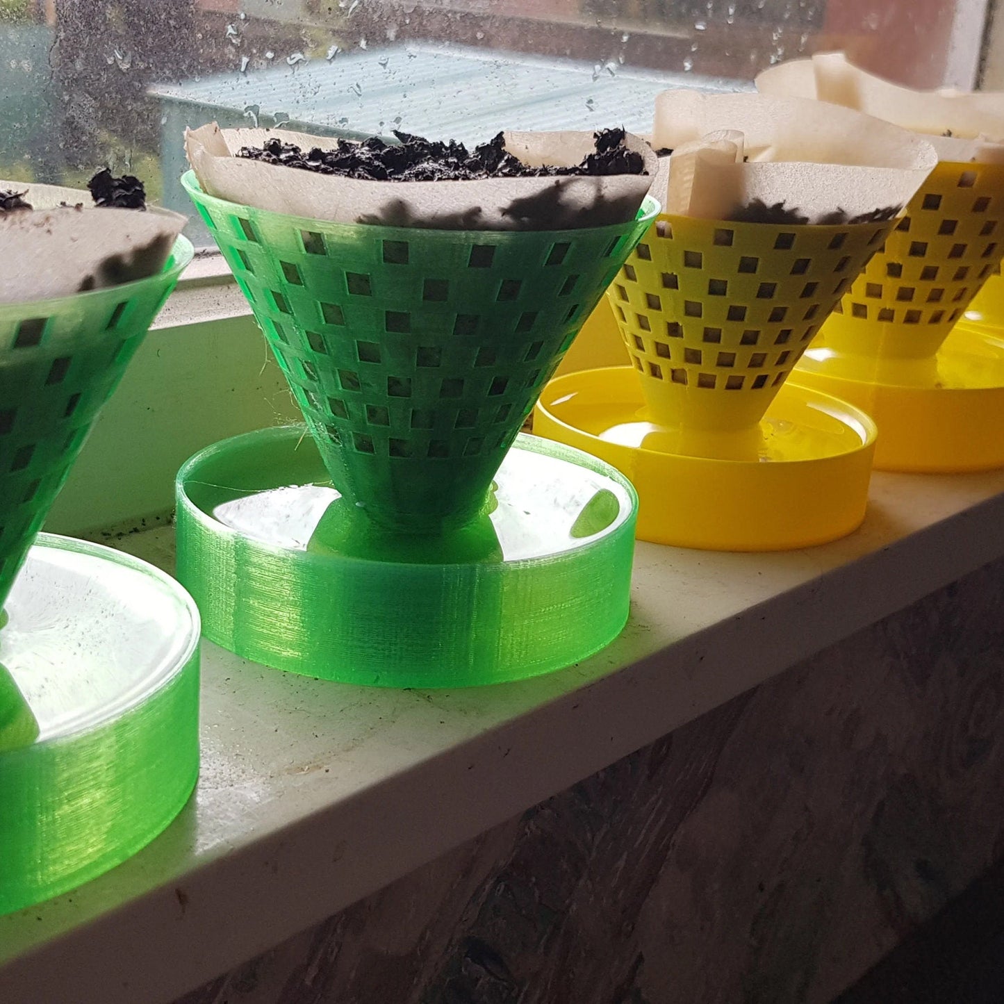 a window sill filled with plastic cups filled with dirt