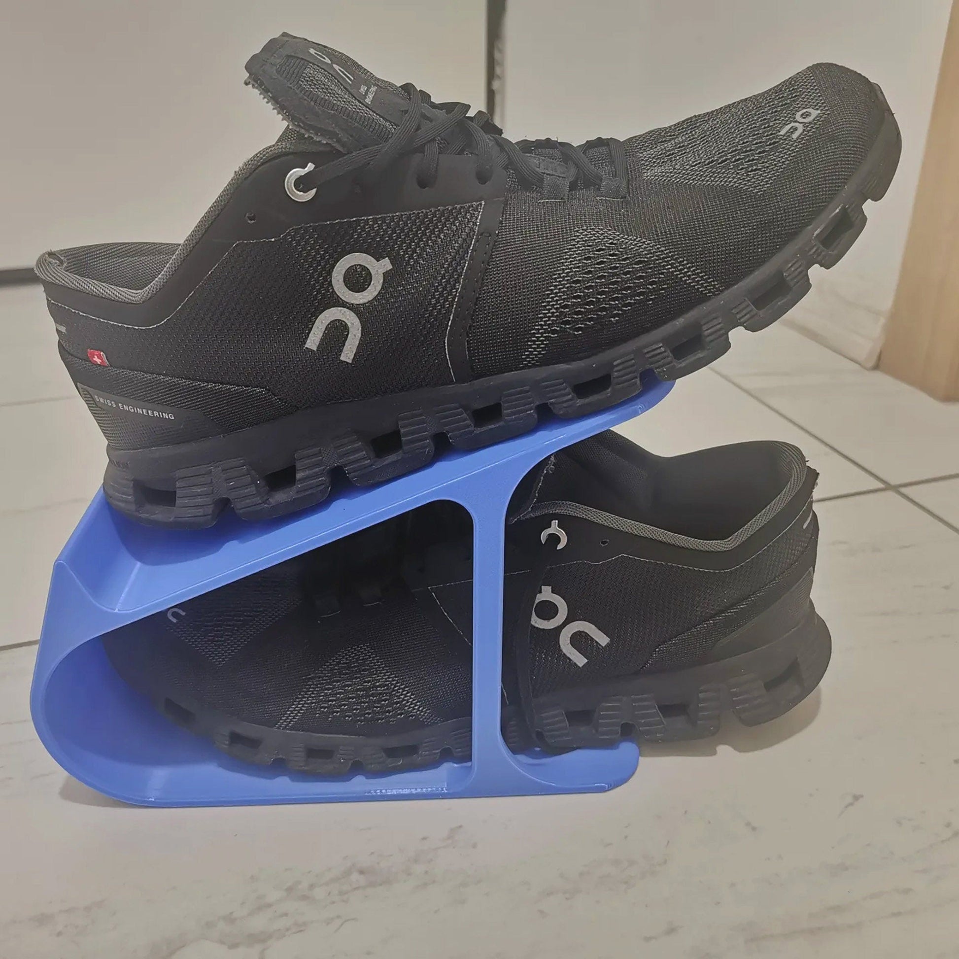 a pair of black running shoes sitting on top of a blue stand