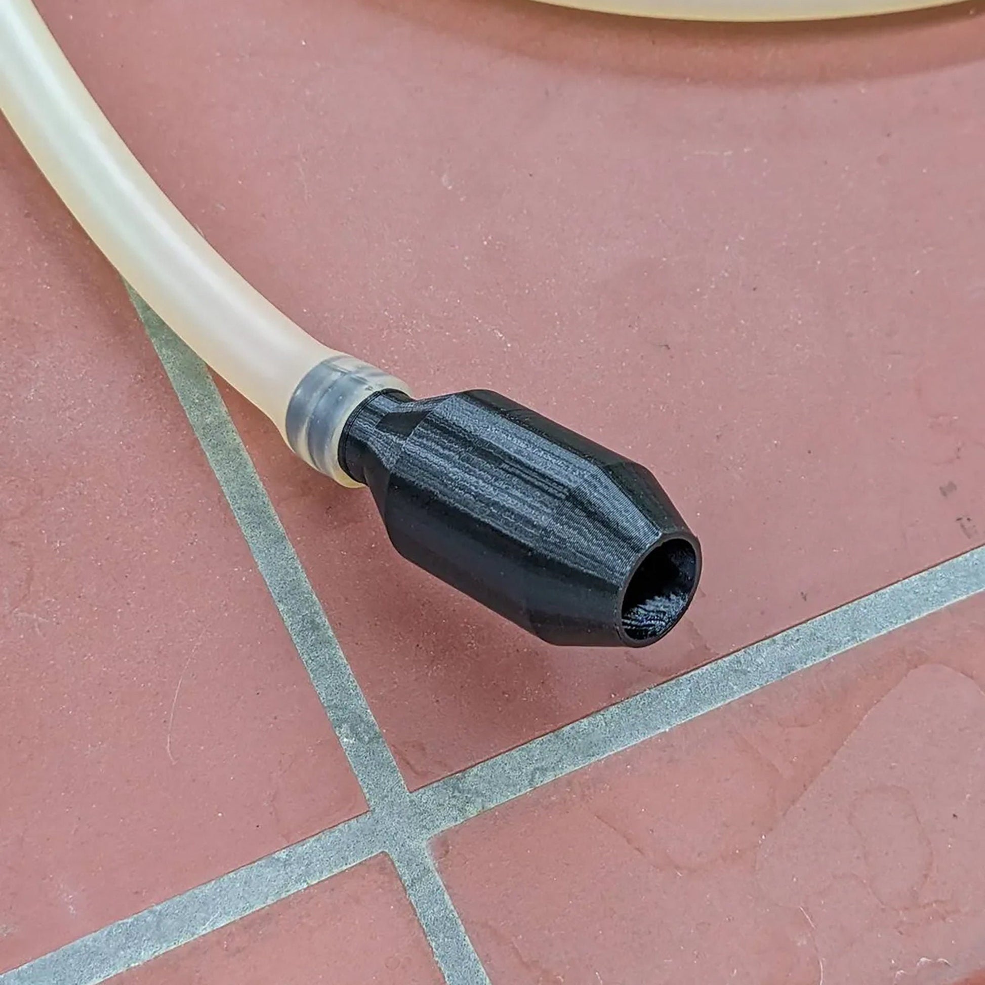 a black and white hose connected to a red tile floor