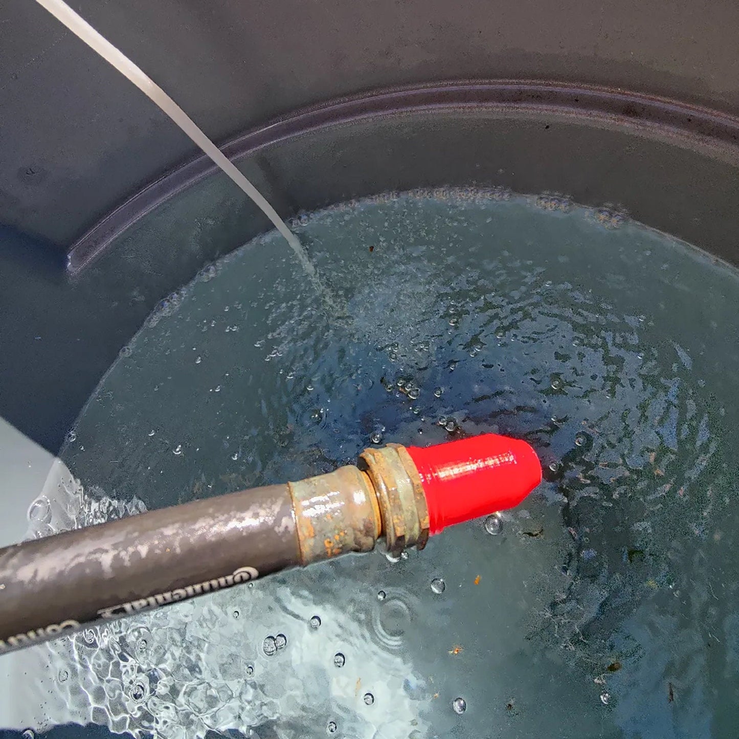 a red pipe sticking out of a bucket filled with water