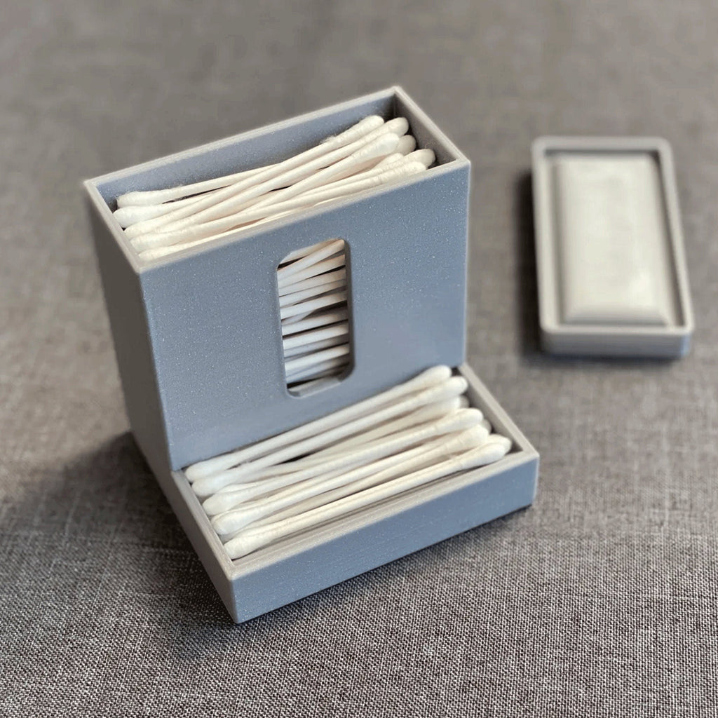 Covered cotton swab dispenser with a front catch tray on a bathroom vanity, view 4