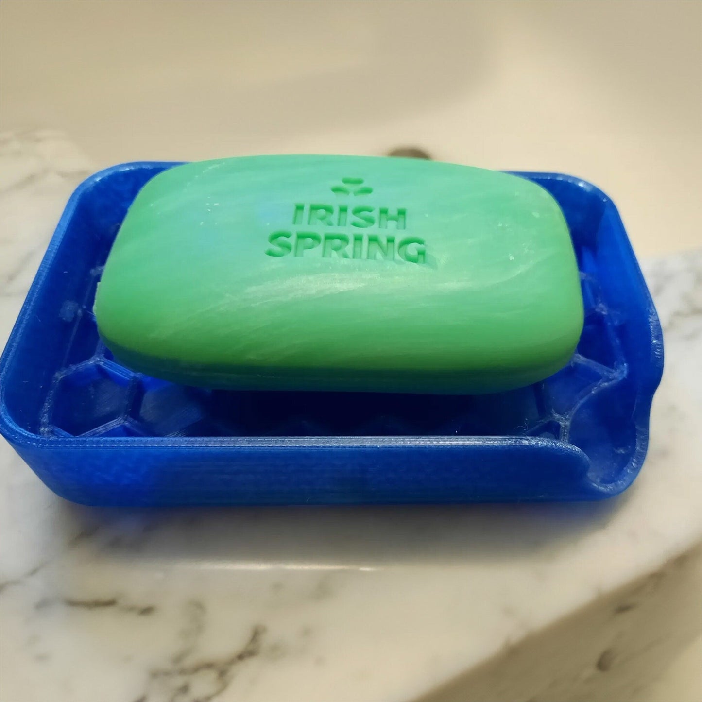 a green and blue soap dish sitting on top of a marble counter