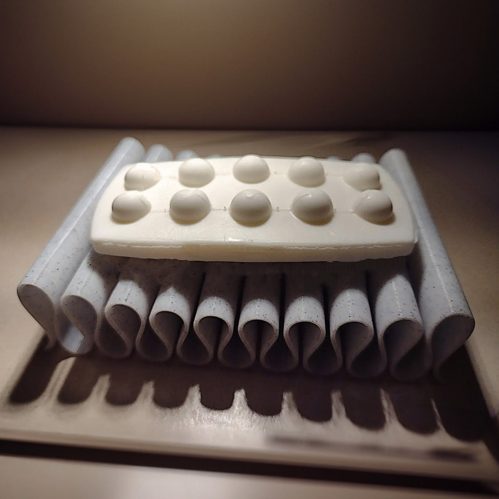 Self-draining ribbed soap dish holding a bar of soap by a sink
