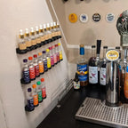 Wall rack holding 40ml SodaStream flavor bottles in a row, view 3