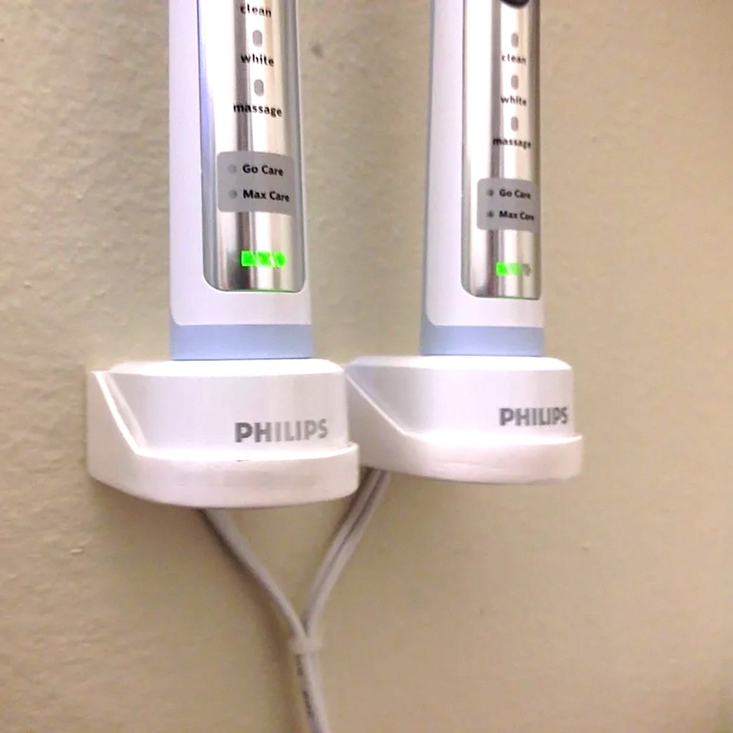 two electric toothbrushes plugged into a wall