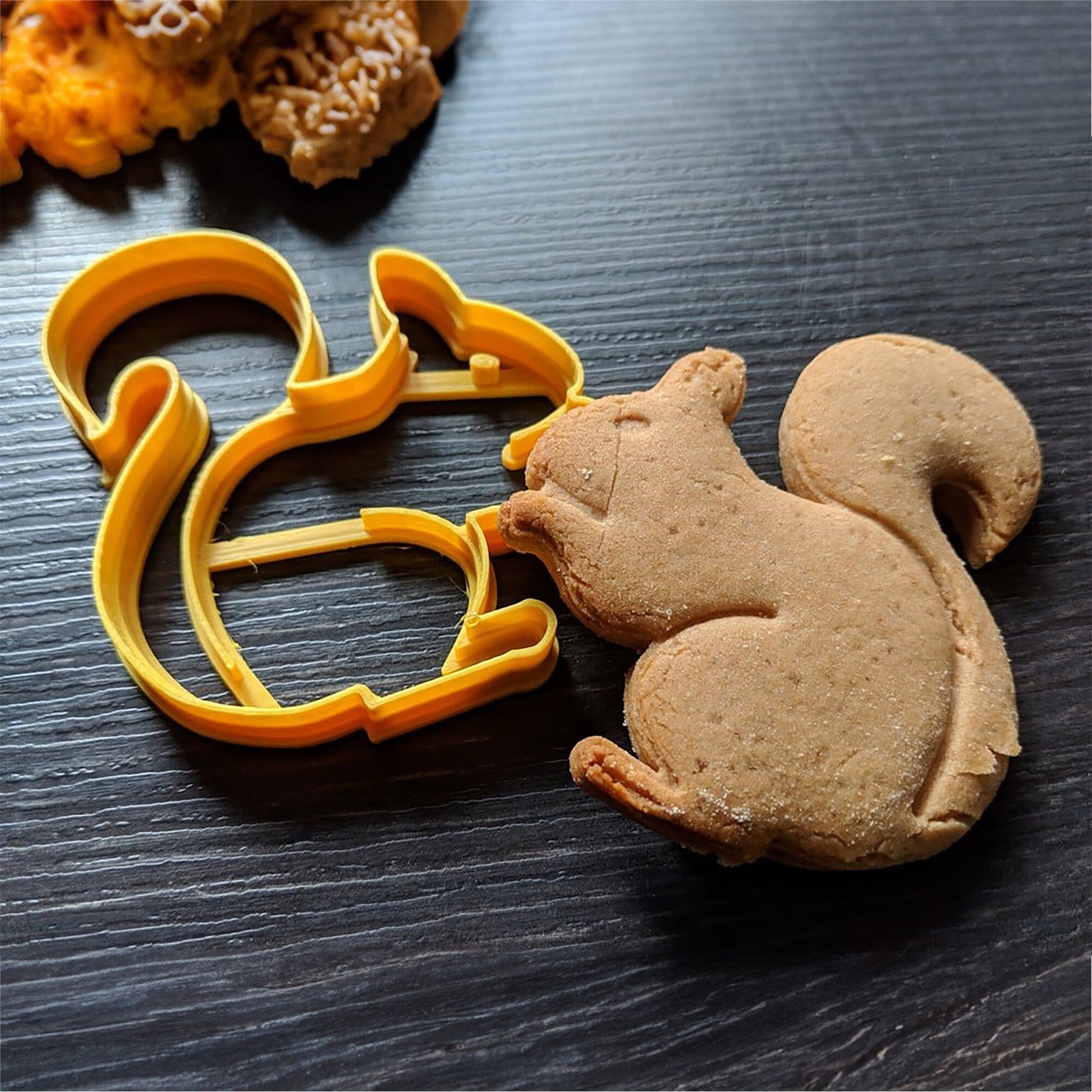 a cookie shaped like a squirrel next to a cookie cutter