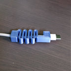 Segmented USB-C cable guard on a MacBook charging cord at the plug, view 2