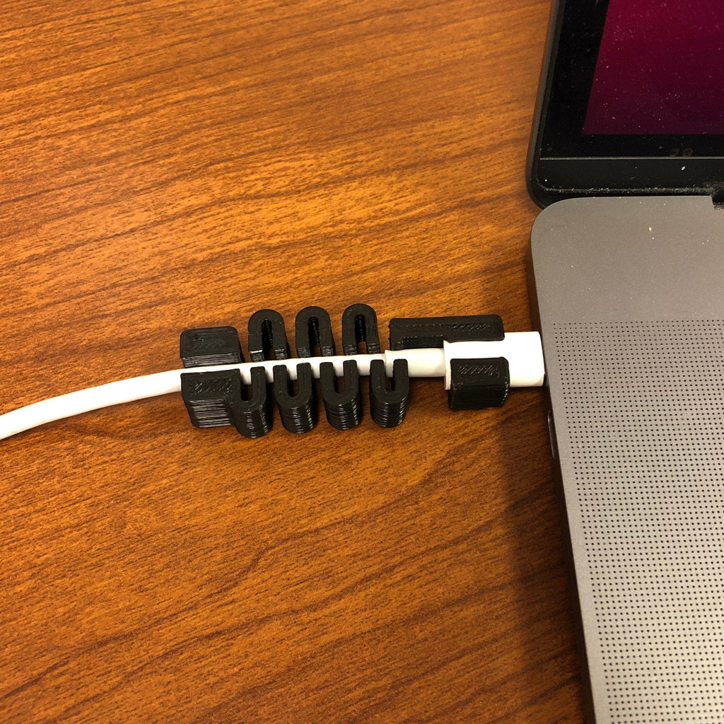 Segmented USB-C cable guard on a MacBook charging cord at the plug