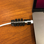 Segmented USB-C cable guard on a MacBook charging cord at the plug