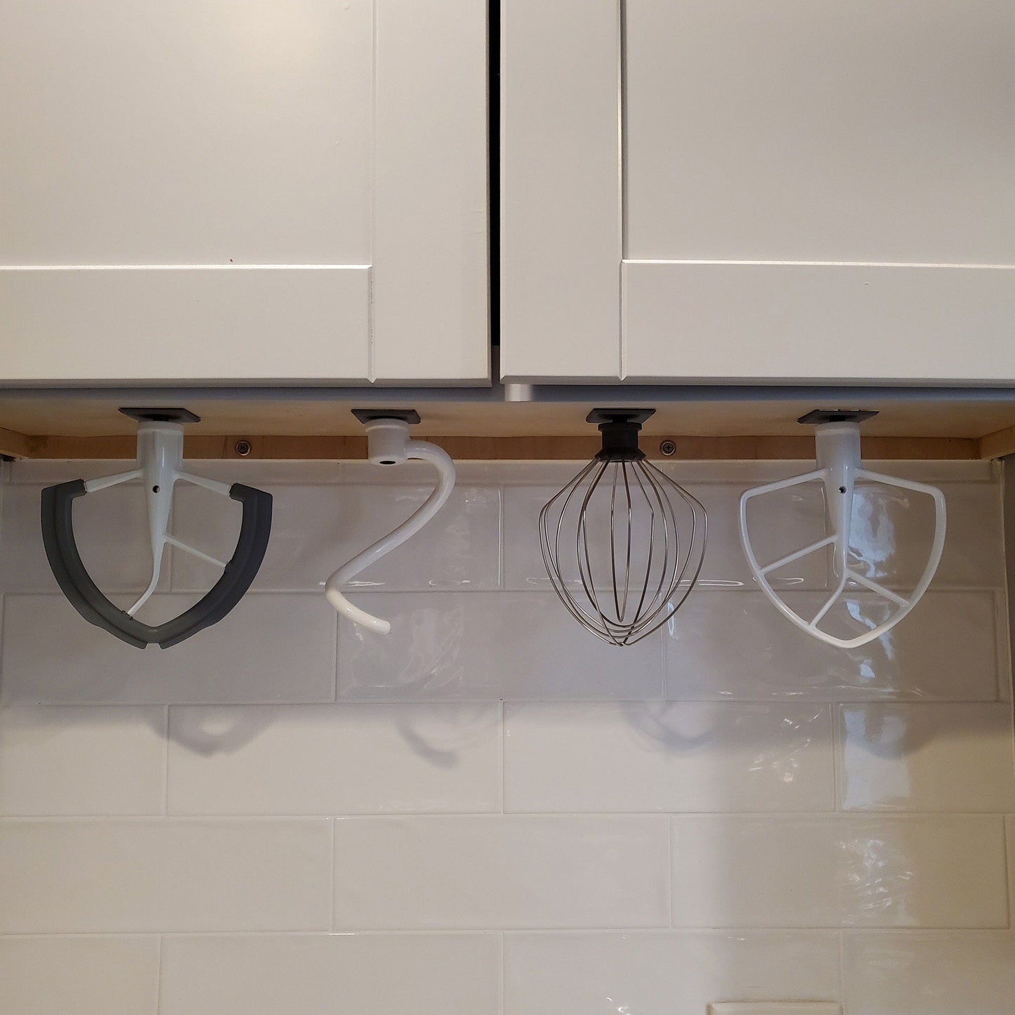 a kitchen with white cabinets and a wire whisk hanging from the ceiling